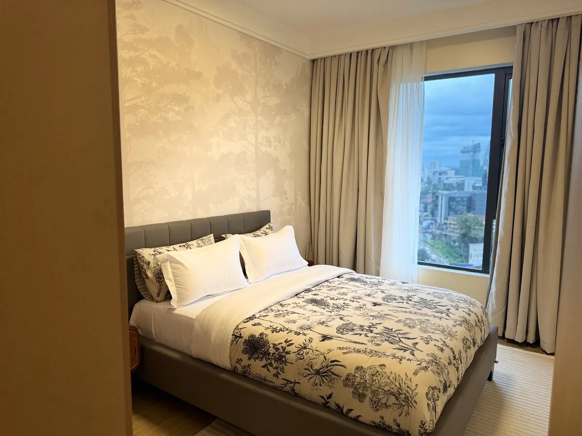 Bedroom with floral bedding and a window over the city