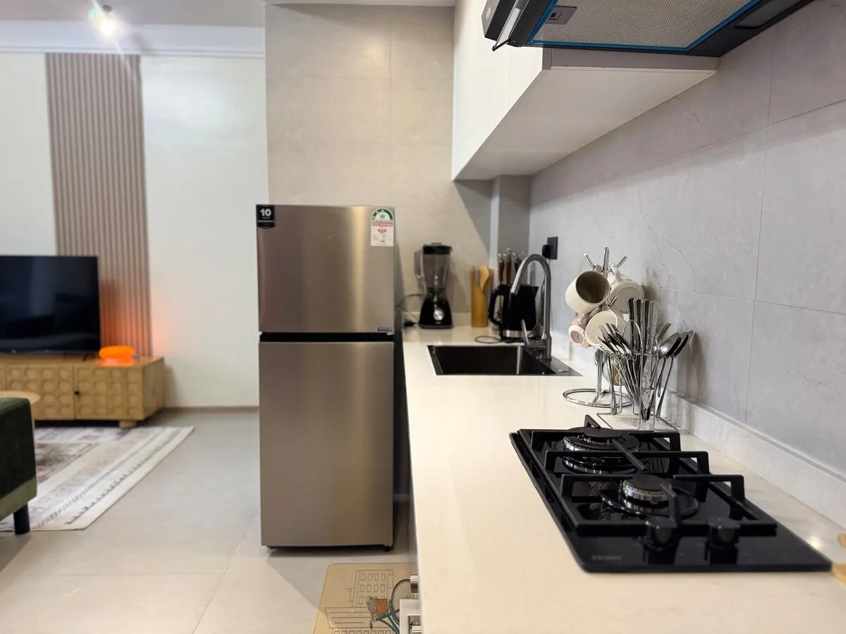 Kitchen counter with gas hob, sink, fridge and utensils