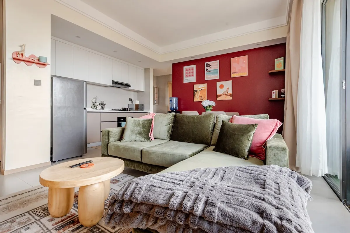 Open-plan living room and kitchen with a red feature wall and framed prints